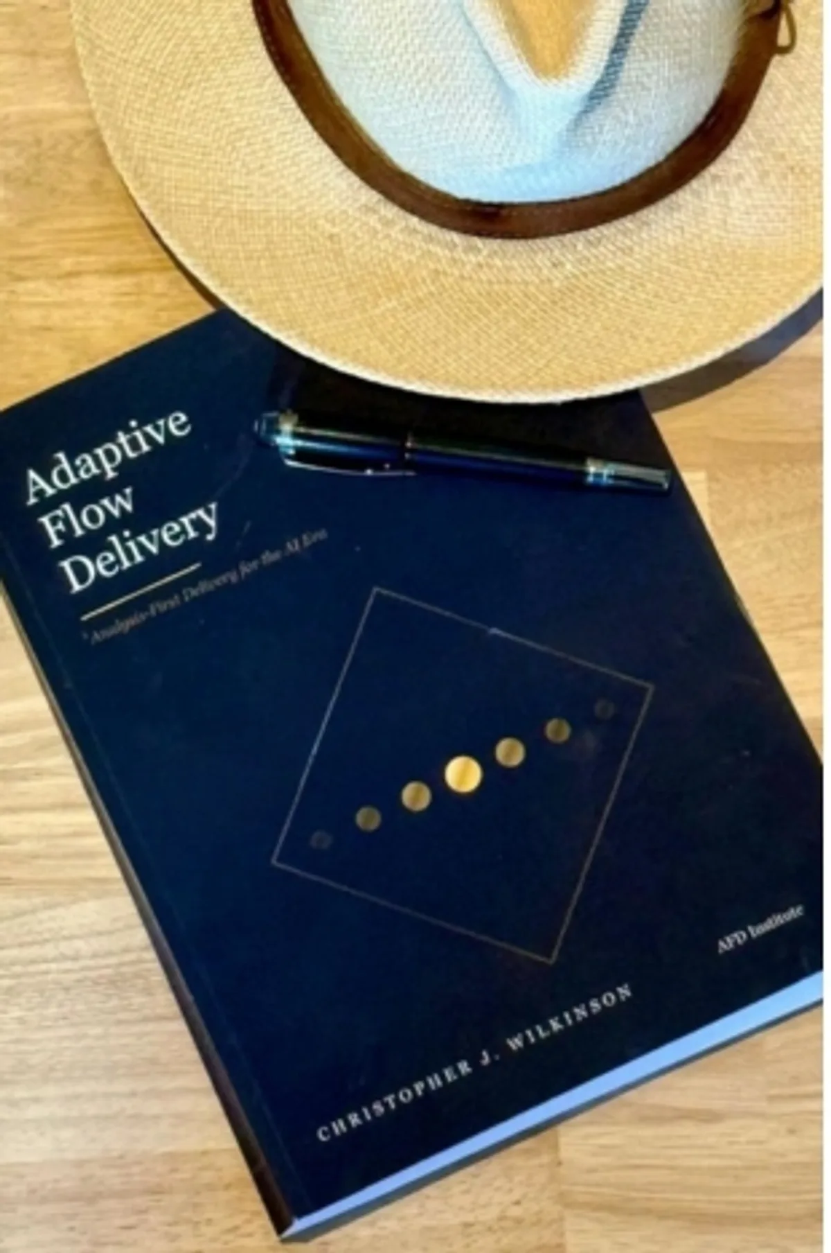 The book Adaptive Flow Delivery by Christopher J. Wilkinson, with a hat and pen